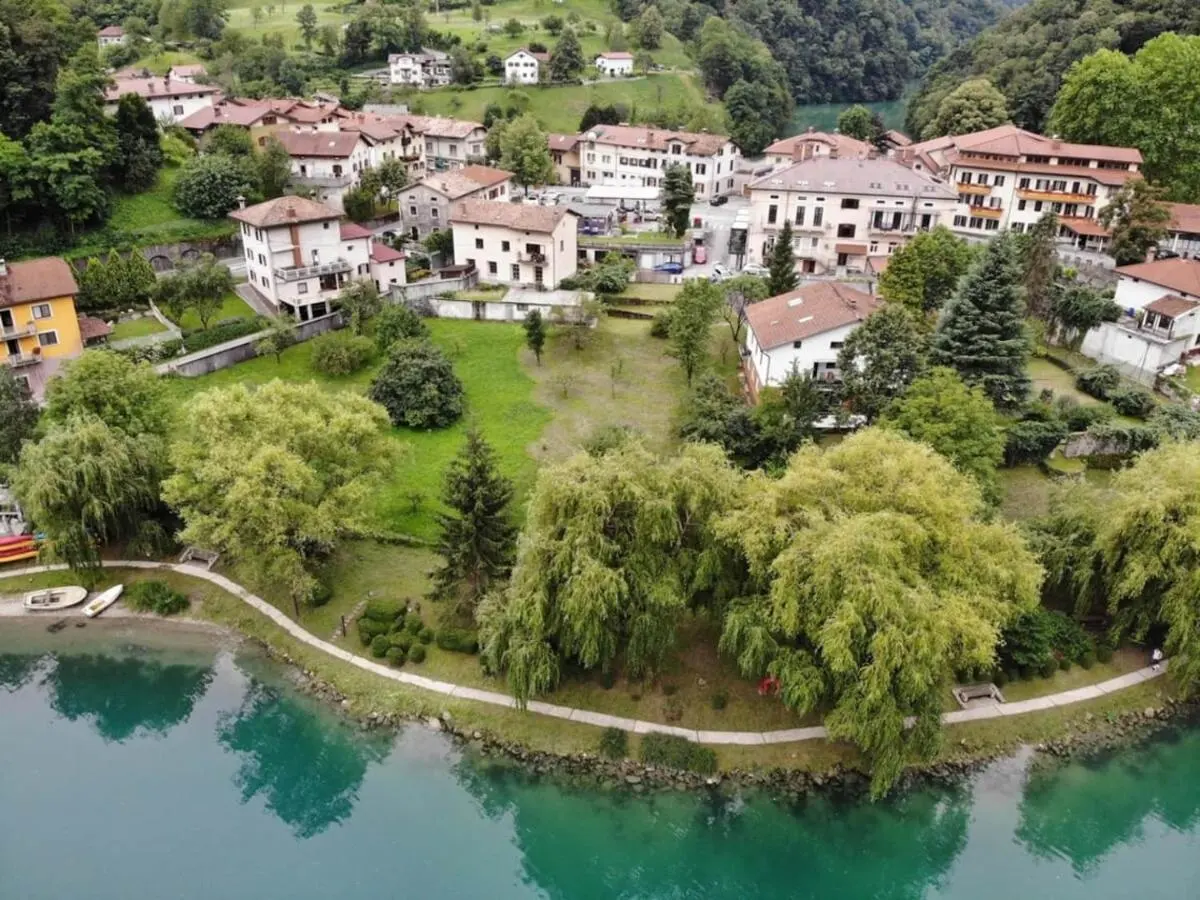 Jezero na Mostu na Soči s sprehajalno potjo ob vodi in vasjo nad njim, posneto iz zraka